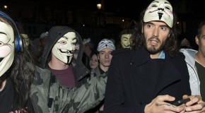 A masked Russell Brand leads Anonymous march against austerity cuts: Funnyman-turned-activist joins protesters as they aim fireworks at Buckingham Palace